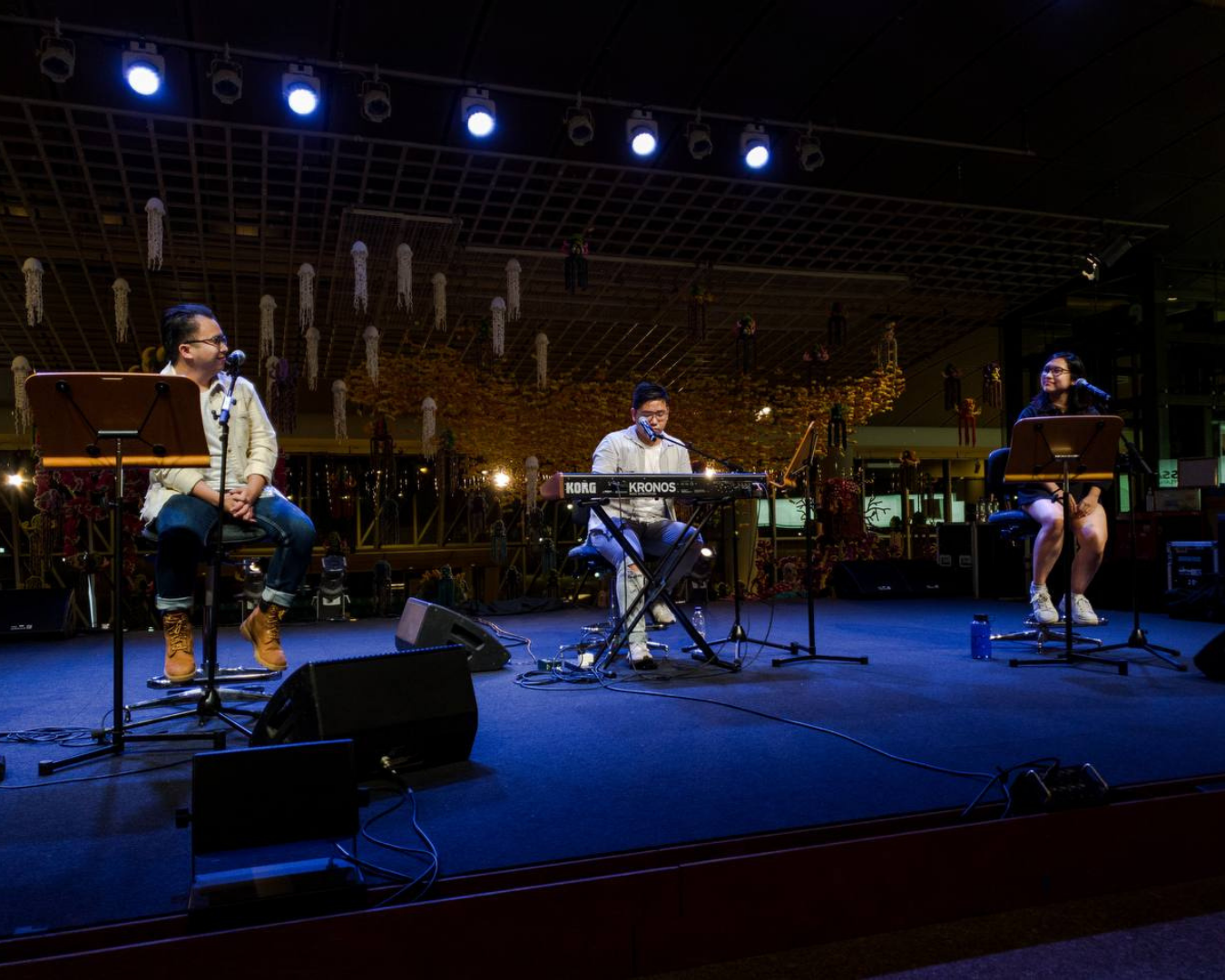 A trio performing on a blue-lit stage at Esplanade