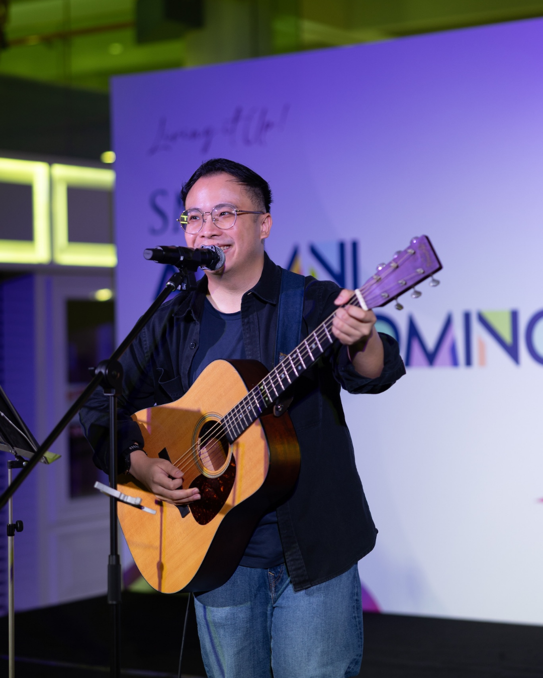 Yongkytown singing and playing an acoustic guitar in front of a purple backdrop